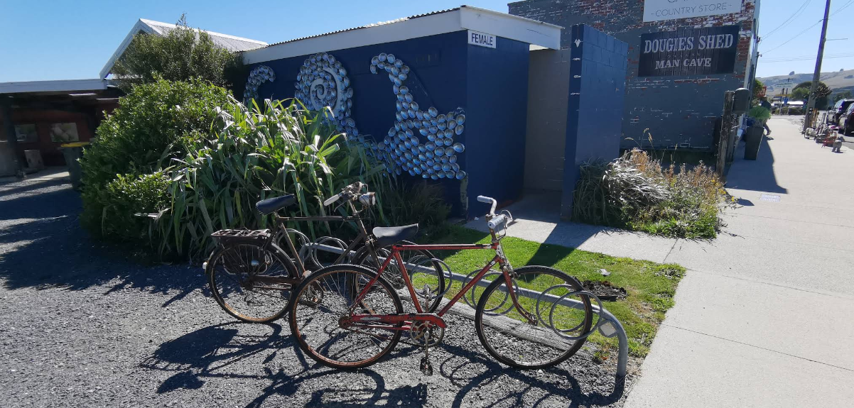 Bicycles and plants outside the shop on a sunny Owaka street