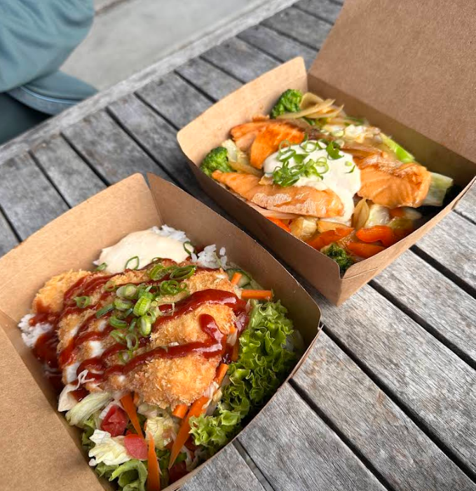 Two Japanese takeaway meals on an outdoor wooden table